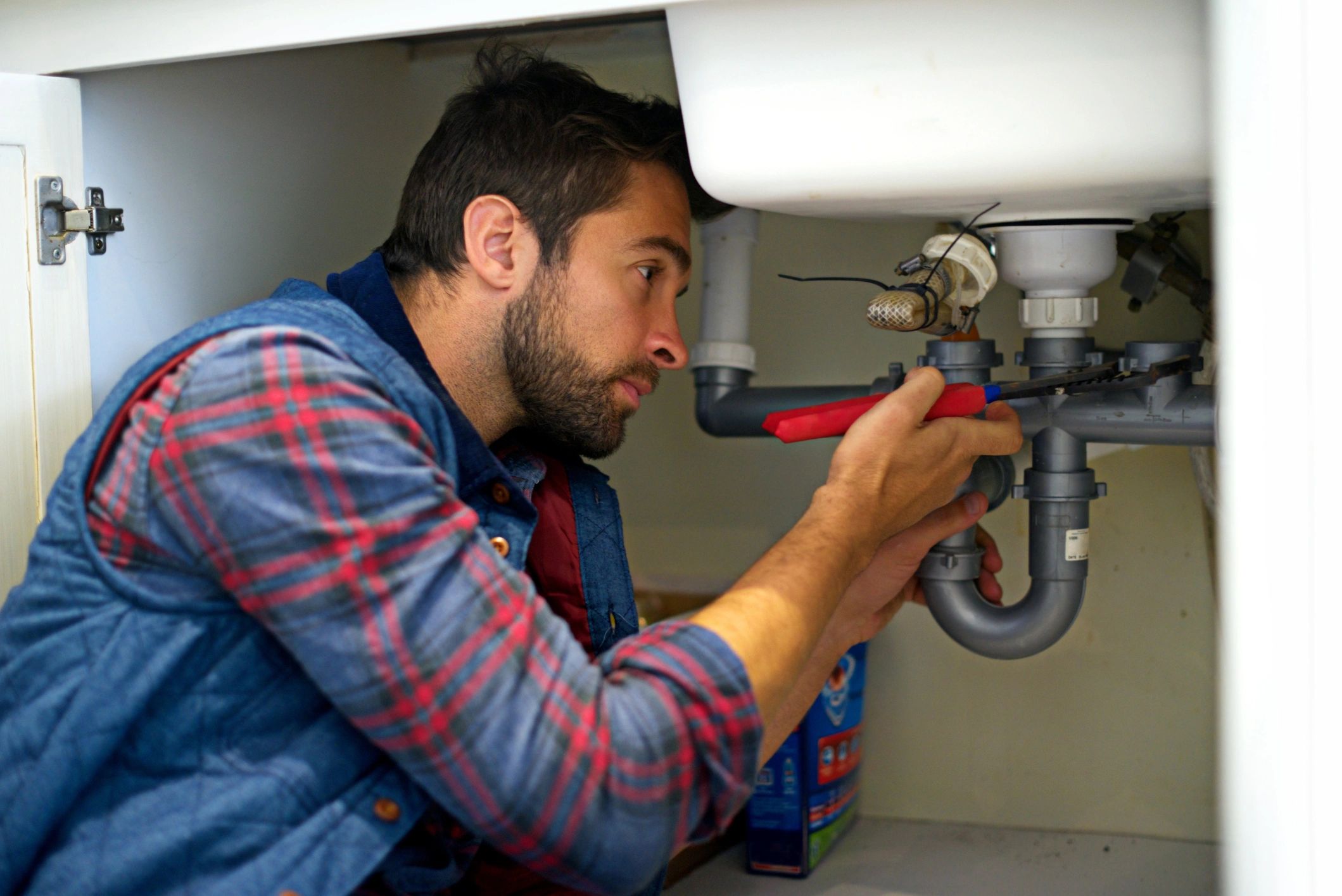 Technician repairing plumbing under a sink